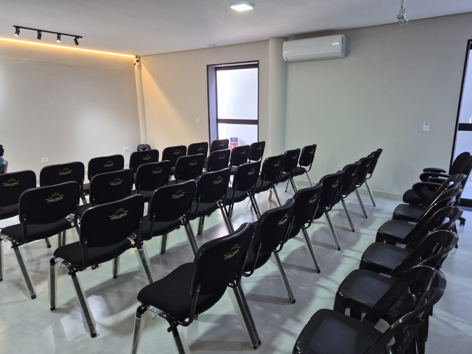 Cadeiras com a marca alinhadas ao longo do corredor lateral, com ar-condicionado.